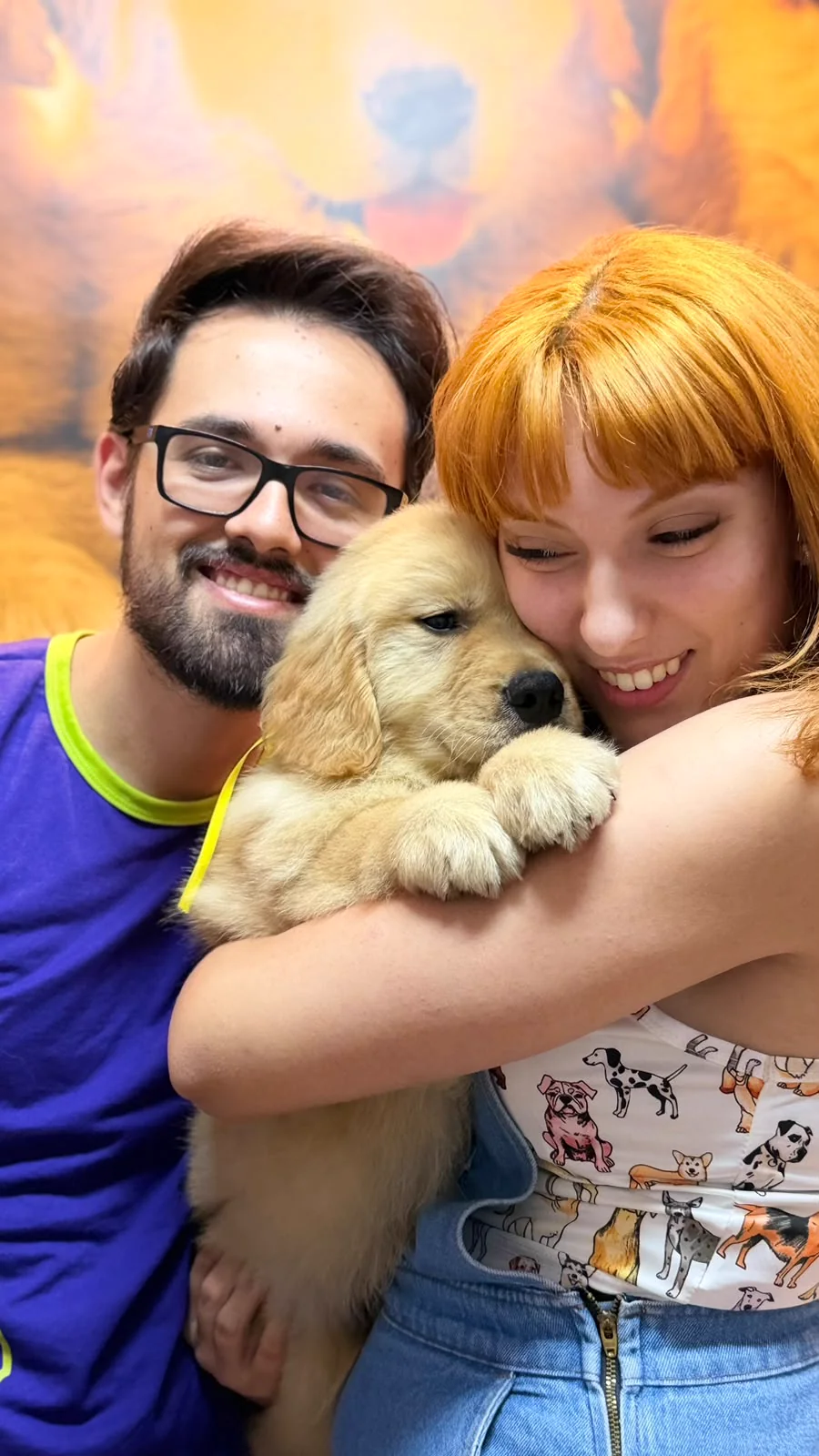 Casal abraçando um filhote de Golden Retriever