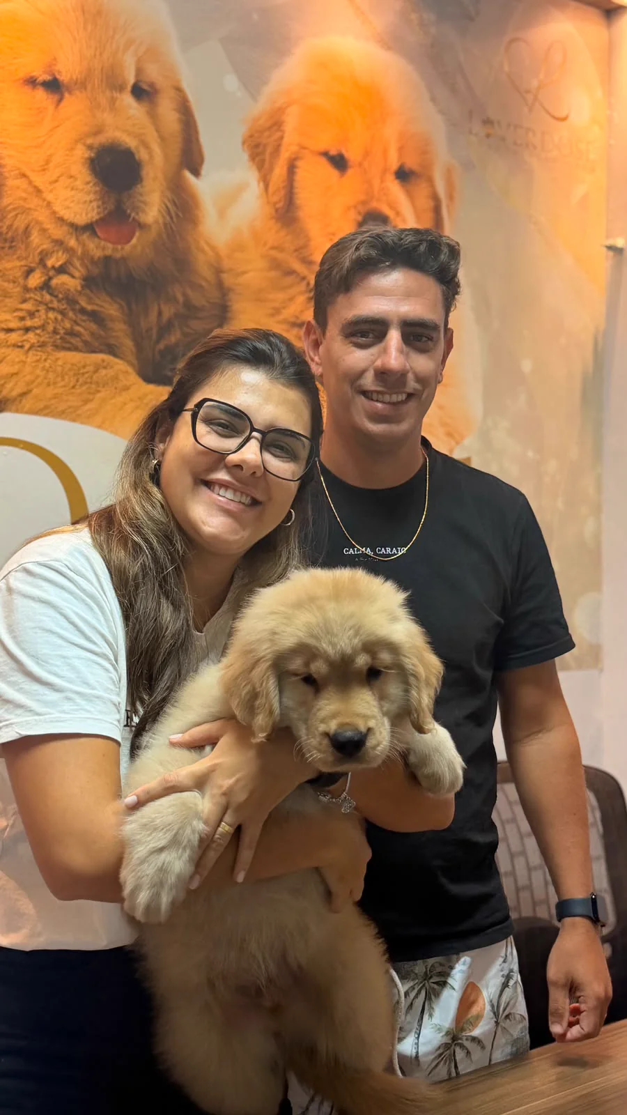 Casal sorrindo com um filhote de Golden Retriever
